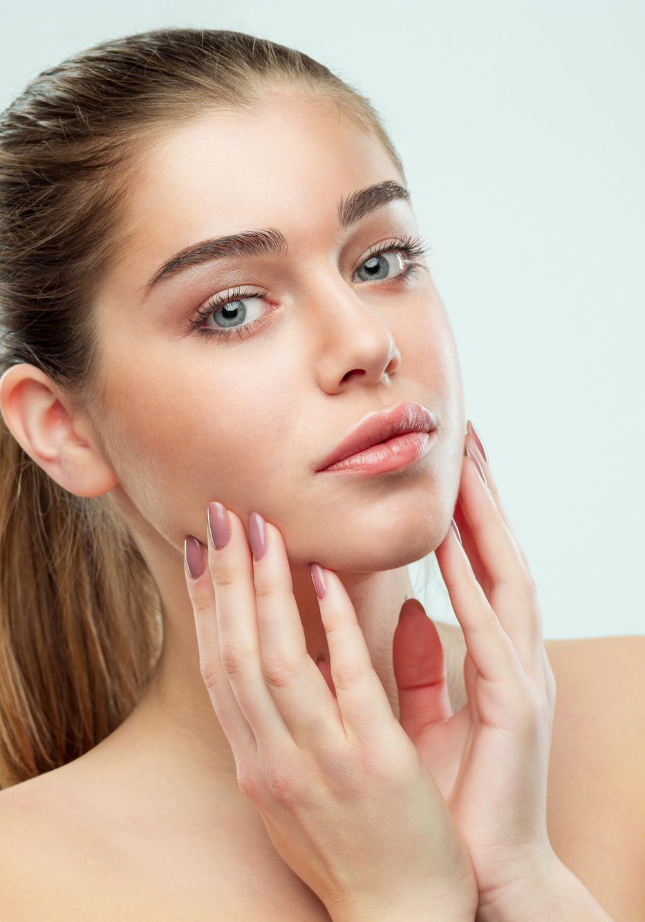 The beautiful female face. The perfect and clean skin of face on gray